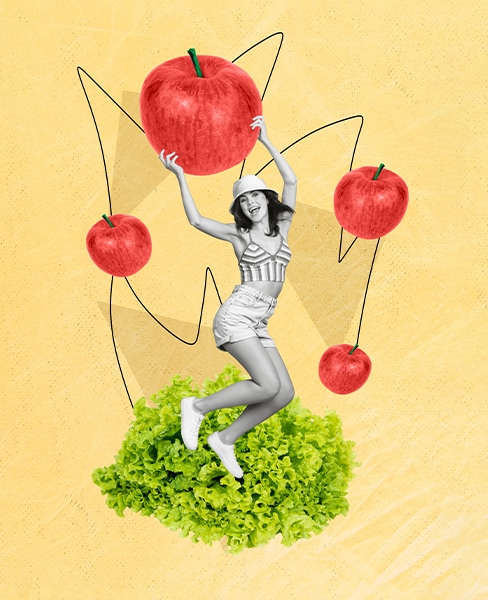 Frau tanzt auf Salat und hält Apfel in der Hand